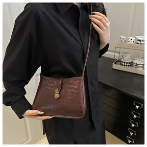 Détail du sac à bandoulière marron foncé effet croco avec boucle en bronze vintage