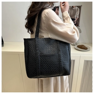 Close-up of black woven leather tote bag texture and reinforced shoulder straps