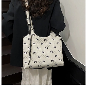 Detail shot of large tote bag featuring chic black polka dots and small ribbon patterns