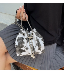 Detail view of the mini cow print bucket bag with silver chain and large pearl charms