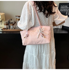 Detail of light pink snake skin tote bag with pearl bow and woven rope handle knots