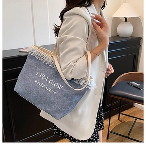 Détail du sac cabas en denim bleu avec bordure en dentelle blanche et logo imprimé