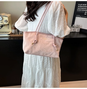 Detail of pink embossed tote bag with knot strap and gold accents on model