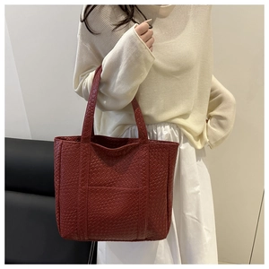 Detailed close-up of dark red woven leather tote bag with fine braided texture detail