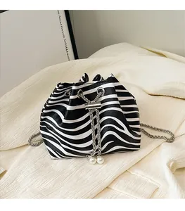 Close-up of zebra print bucket bag featuring a silver chain and elegant pearl tassel detail