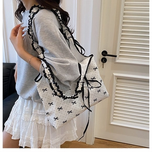 Detail of ruffle shoulder strap on white tote bag with black polka dots and bows