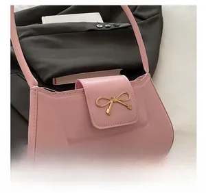 Detail of pink PU leather underarm bag with iconic golden metallic bow clasp