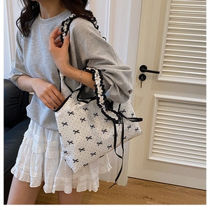 Detail of white canvas tote with black bow print and ruffled handle for daily use