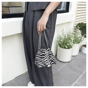 Detail of zebra print bucket bag with silver chain strap and pearl drawstring charm