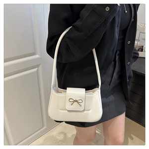 Détail d'un sac baguette crème chic avec boucle en métal doré et nœud élégant