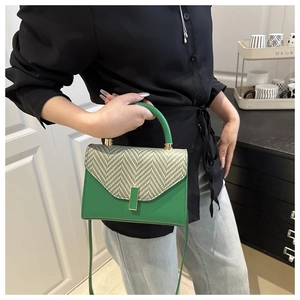 Detail of green plaid crossbody bag with circular handle and elegant metal buckle closure