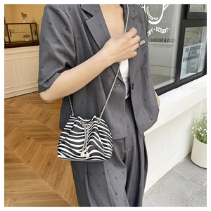 Detailed view of zebra print bucket bag with pearl drawstring and metal chain strap
