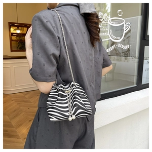 Detail of zebra pattern bucket bag with pearl charm and silver chain strap on model