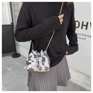 Detail of mini bucket bag with cow print fabric, silver chain and pearl drawstring