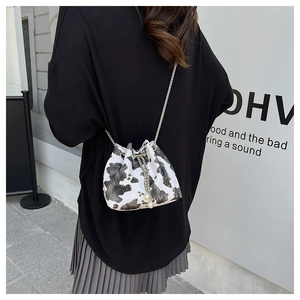 Detail shot of mini cow print bucket bag with silver metal drawstring and pearl tassels