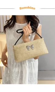 Detail showing natural straw weave texture with a silver metallic bow and black handle