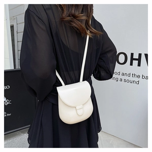 Rear view of a minimalist cream white mini crossbody bag worn over a black casual coat