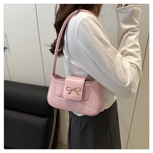 Détail d'un sac à bandoulière rose avec un nœud doré en métal et texture en cuir PU lisse