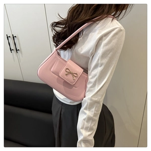 Close-up of pink leather baguette bag with a golden bow buckle and fine stitching