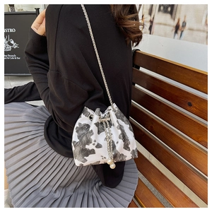 Cow print bucket bag with silver chain strap and pearl details on a model