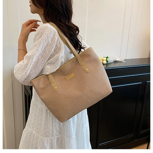 Détail du sac cabas beige avec motifs embossés et plaque métallique dorée décorative