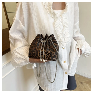 Detail view of leopard print bucket bag featuring metal chain and white pearl charms