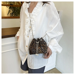 Detail of leopard print bucket bag featuring chain drawstring and large pearl accents
