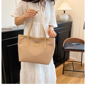 Gros plan détaillé d'un sac cabas beige avec des motifs géométriques embossés