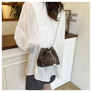 Detail view of leopard print bucket bag with metal chain and pearl drawstring charms