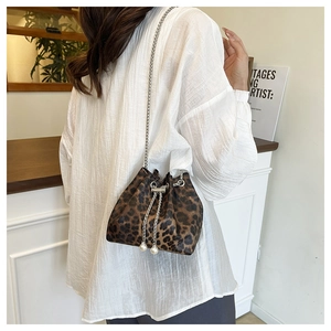 Detail view of leopard print bucket bag with elegant pearl drawstring and chain strap
