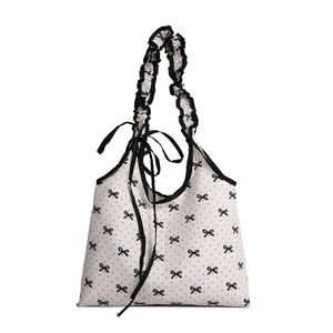 White canvas tote bag with black polka dots, bow patterns and ruffled shoulder strap
