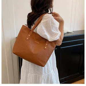 Détail du sac cabas marron en cuir texturé avec gaufrage géométrique et logo doré élégant