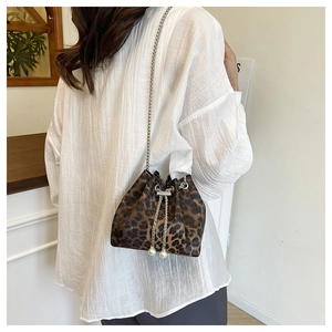 Detail of leopard print bucket bag featuring silver chain strap and pearl drawstring charms