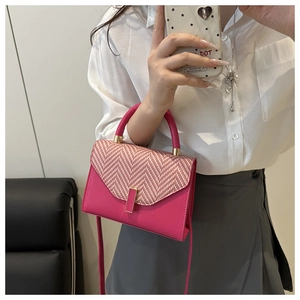 Close-up of fuchsia crossbody bag with herringbone fabric and golden hardware detail