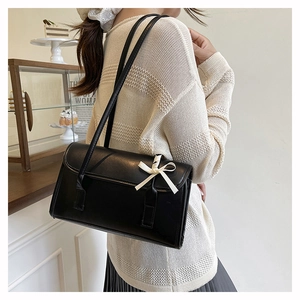 French ballet style black baguette bag with white ribbon bow and matte leather finish