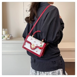 Close-up of cute cherry print handbag with red woven handle and gold flower lock