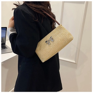 Close-up of the woven straw bucket bag texture and elegant silver metal bow detail