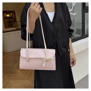 Detail of light pink PU leather shoulder bag with decorative cream silk bow and ribbon