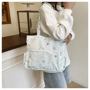 Close-up of light blue plaid tote bag with star patterns and multi-pocket design detail