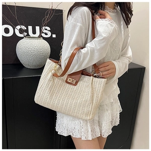Détail du tissage beige avec rabat en cuir marron et fermoir doré sur le sac cabas