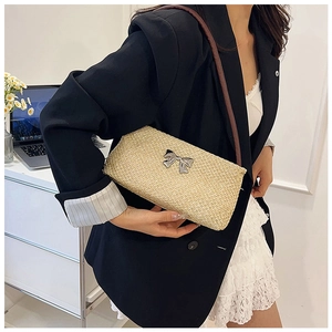 Detail view of woven bucket bag with silver bow buckle and slim brown leather strap