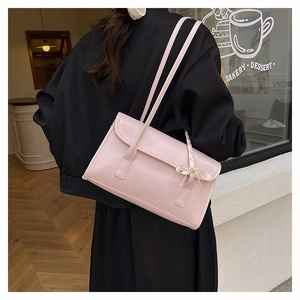 Detail of a pink French ballet baguette bag featuring a silk bow and double straps