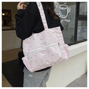 Detail der rosa karierten Canvas-Schultertasche mit Sternen, Bären und vorderem Reißverschluss