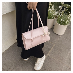 Detail of light pink shoulder bag with elegant white ribbon bow and sleek leather texture