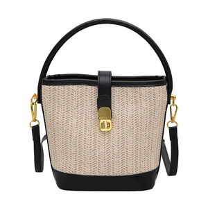 Chic straw bucket bag with black leather trim and gold twist lock for summer vacations