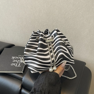 Zebra print drawstring bucket bag with silver chain and pearl accents on black surface