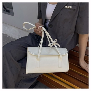 Detailed close-up of a white ballet-style baguette bag with elegant bow strap details