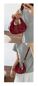 Détail du sac hobo en cuir verni rouge foncé avec finition brillante et ferrures dorées