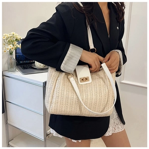 Détail d'un sac cabas tissé beige avec lanières en cuir blanc et fermoir tournant doré