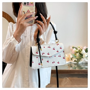 Selfie miroir montrant le sac bandoulière à motif cerise avec poignée noire et anneaux